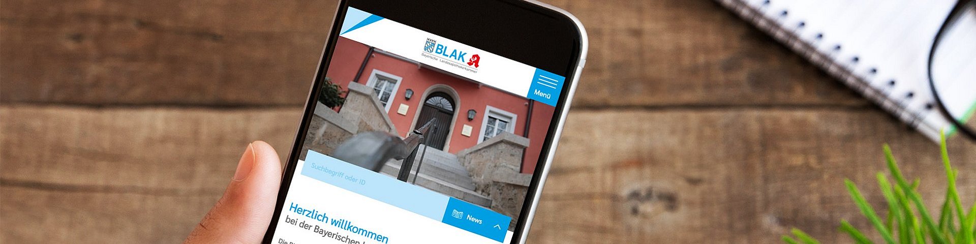 Der neue Webauftritt der Bayerischen Landesapothekerkammer. Es ist ein Smartphone zu sehen, auf welchem die Website der BLAK aufgerufen ist.